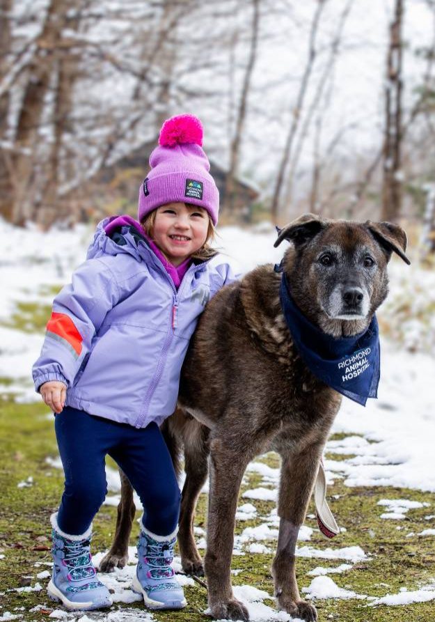 Young girl with family dog standing outside Richmond Animal Hospital clinic in Richmond, Vermont